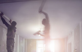 Photo of two men working on a ceiling.