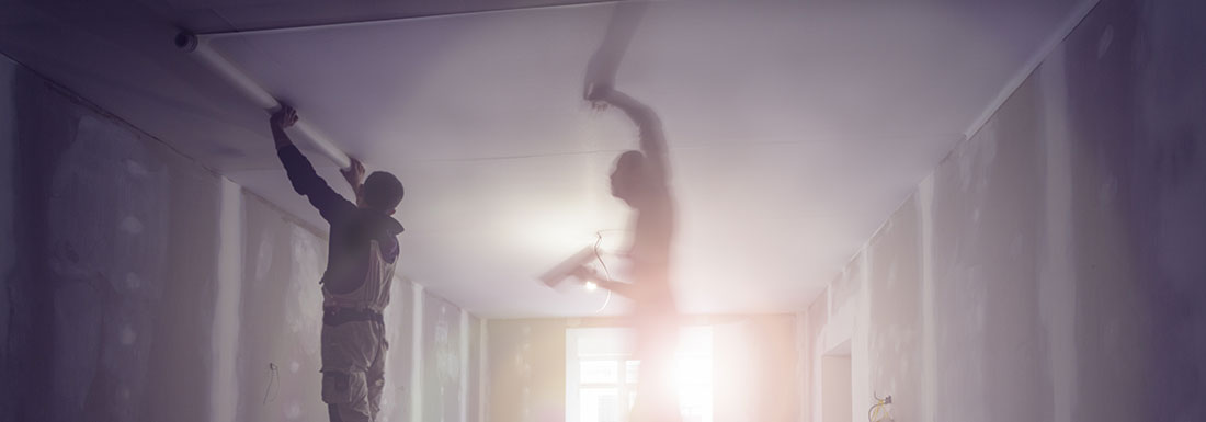 Photo of two men working on a ceiling.